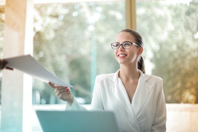 a person sitting at a desk handing away a piece of paper