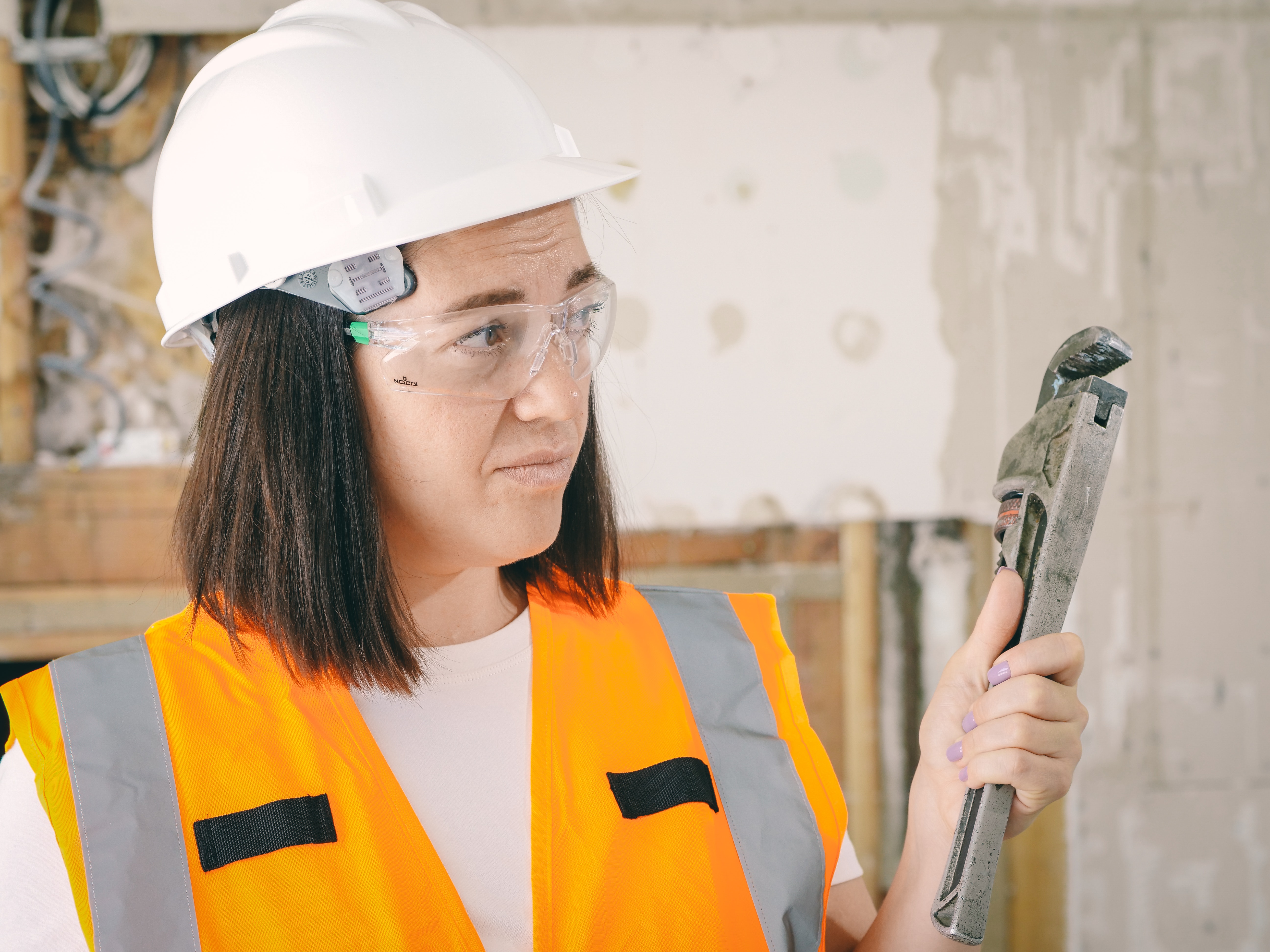 A handywoman holding a large wrench.